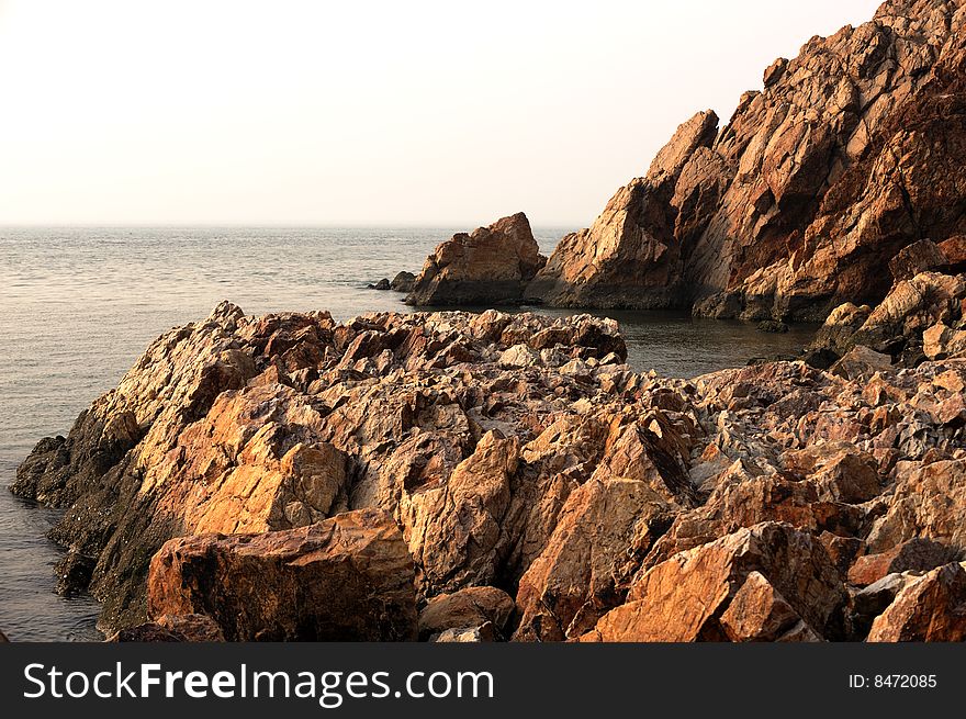 Red rock on side of sea