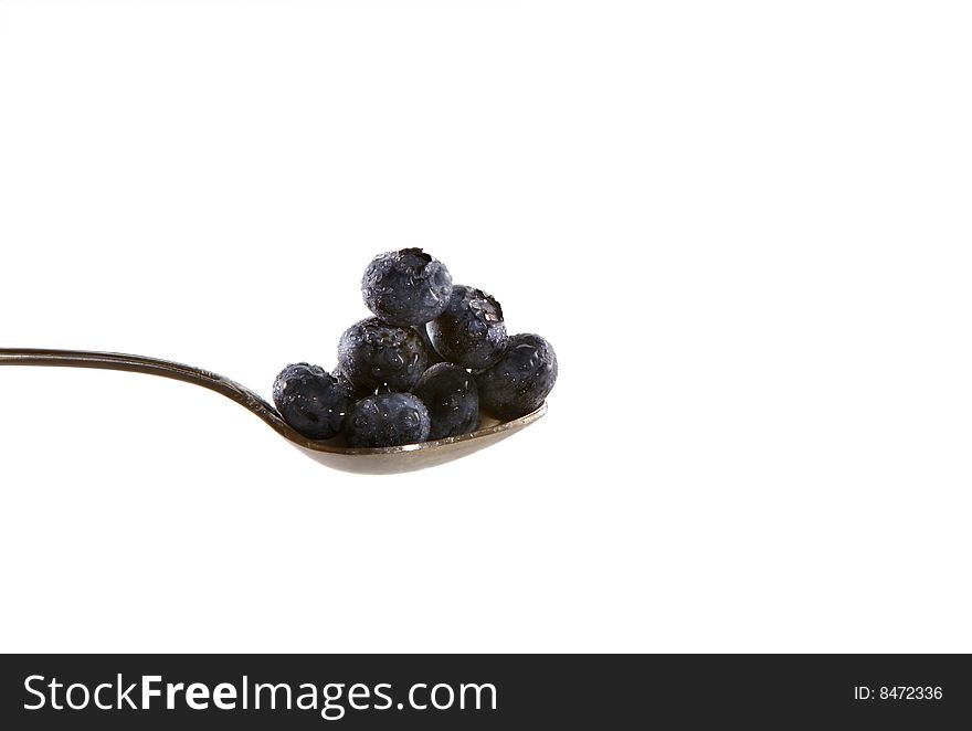Blueberries on a spoon appear in front of a white background. Isolation with clipping path. Blueberries on a spoon appear in front of a white background. Isolation with clipping path.
