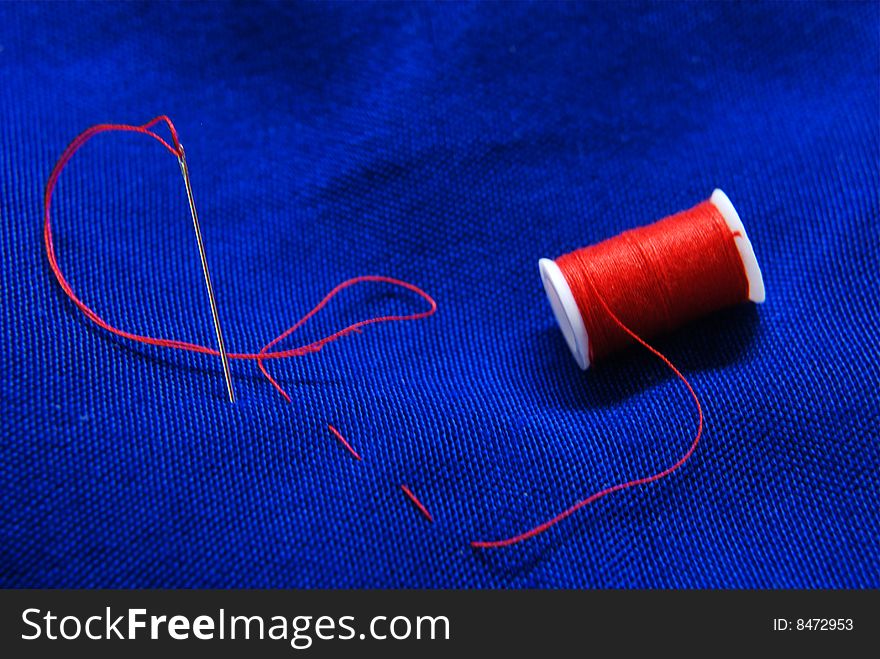 Needle and red thread on blue background. Needle and red thread on blue background