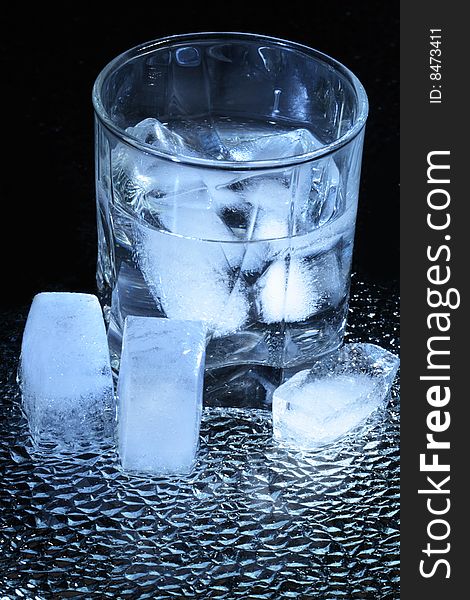 Ice cubes lying near wineglass on dark background. Ice cubes lying near wineglass on dark background