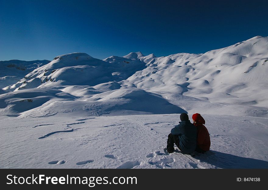 Couple admiring mountain view on the summit in alps in wiinter
