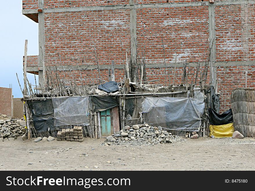 A makeshift shanty house built along a large brick biulding