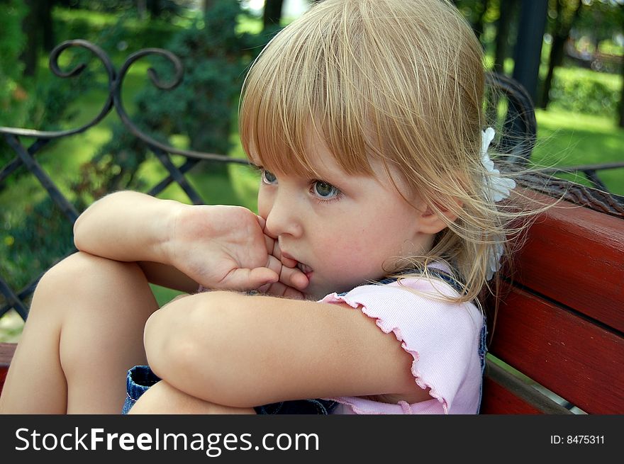 Thoughtful little girl  sit in park on bench. Thoughtful little girl  sit in park on bench