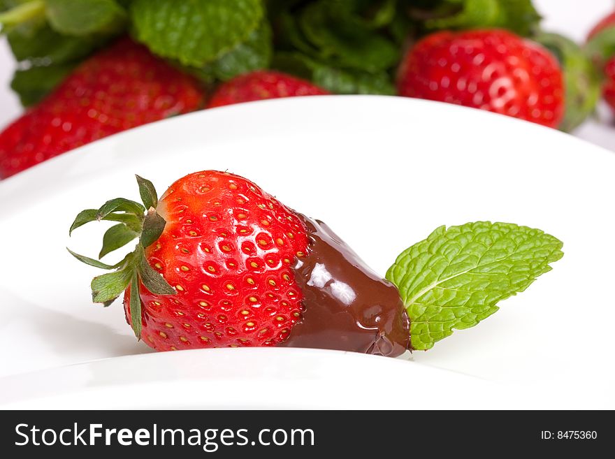 A strawberry dipped on chocolate with fruit background