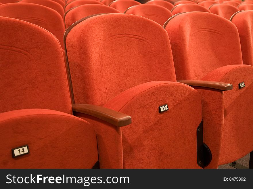 Seat number thirteen. Row of red chairs in auditorium. Seat number thirteen. Row of red chairs in auditorium.