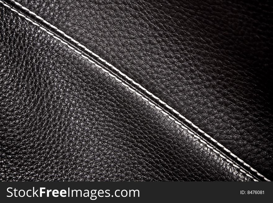 Black leather background stitched up by white thread