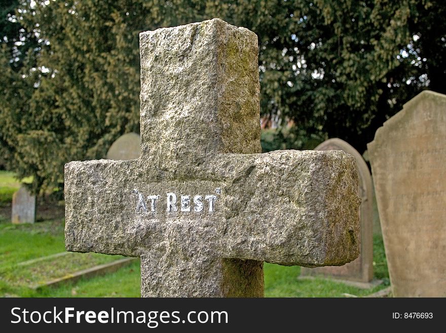 Cross Gravestone in a cemetery with other gravestones in the background