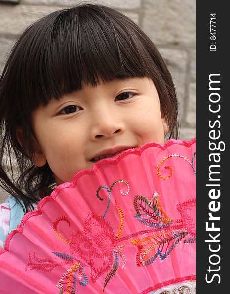 Chinese Girl holdling Pink Fan Up To Her Face. Chinese Girl holdling Pink Fan Up To Her Face