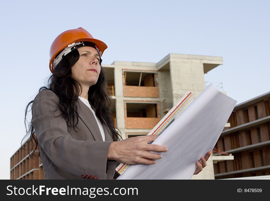 Female architect looking at blueprint in front of construction site