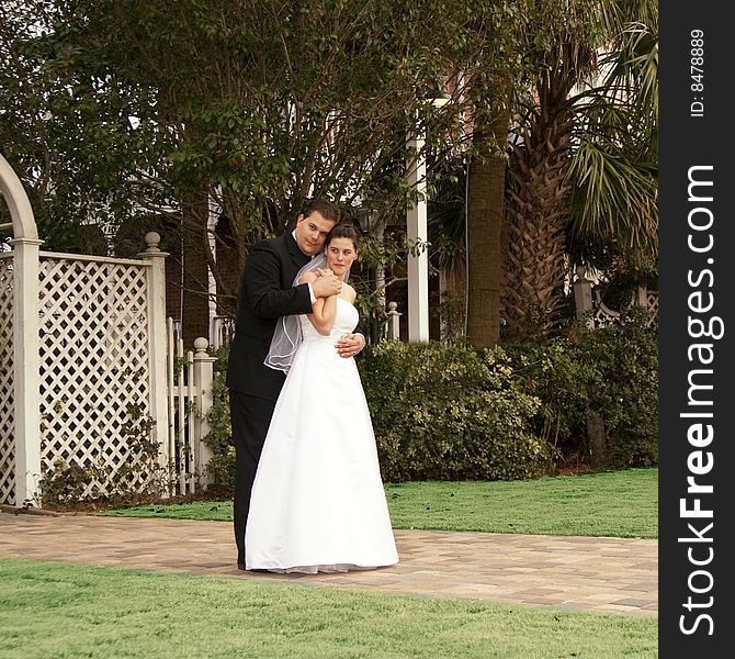 Newlyweds kissing on stone path in garden. Newlyweds kissing on stone path in garden