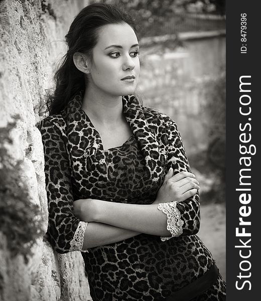 Beautiful girl standing near stone wall black-and-white shot. Beautiful girl standing near stone wall black-and-white shot