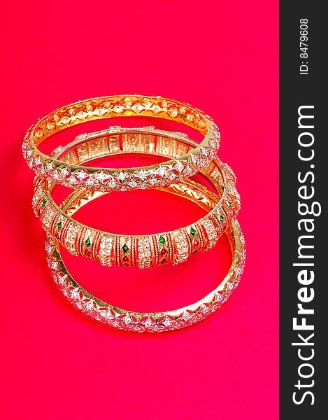 Golden bangles isolated on coloured background.