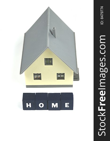 A miniature house with the word home in front of it. A miniature house with the word home in front of it