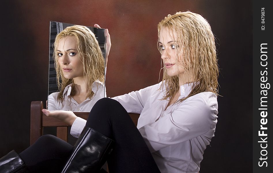Curly wet haired blond sitting in chair looking at camera through mirror. Curly wet haired blond sitting in chair looking at camera through mirror