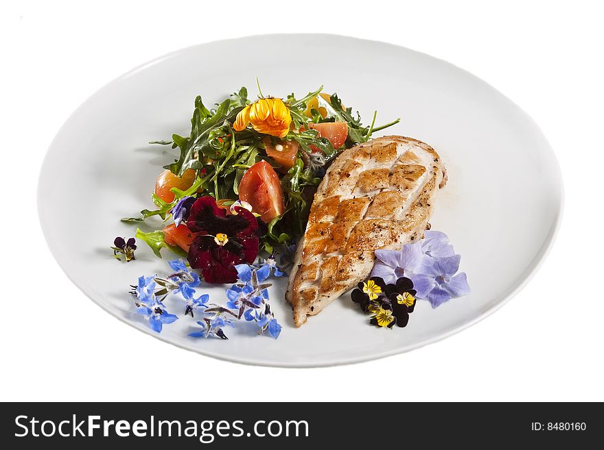 Grilled chicken breast served with salad and garnished with edible flowers