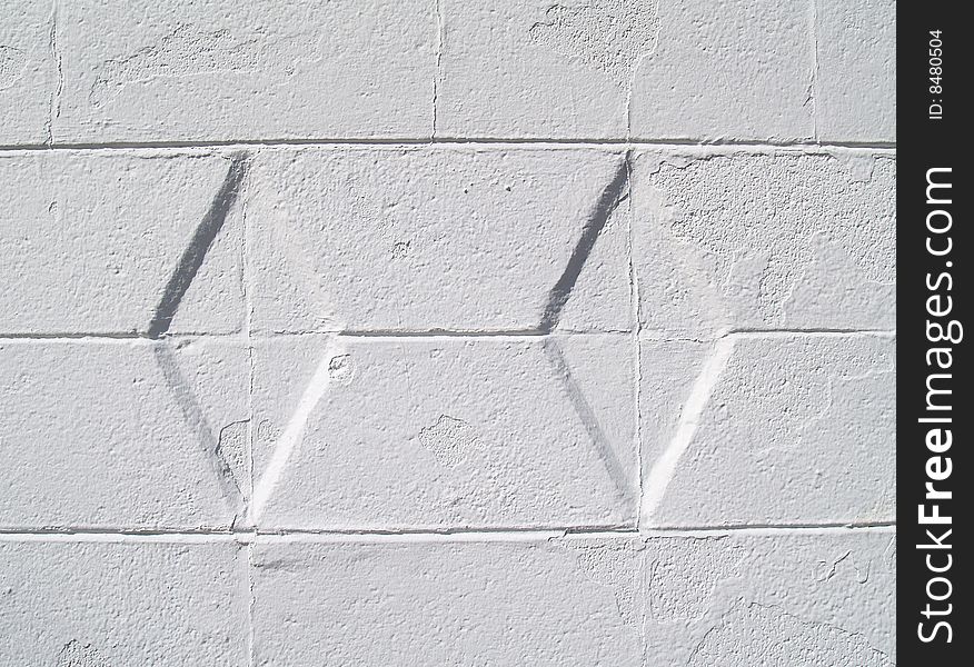 Close-up view of a white painted brick or block exterior wall with diamond texture. Close-up view of a white painted brick or block exterior wall with diamond texture.
