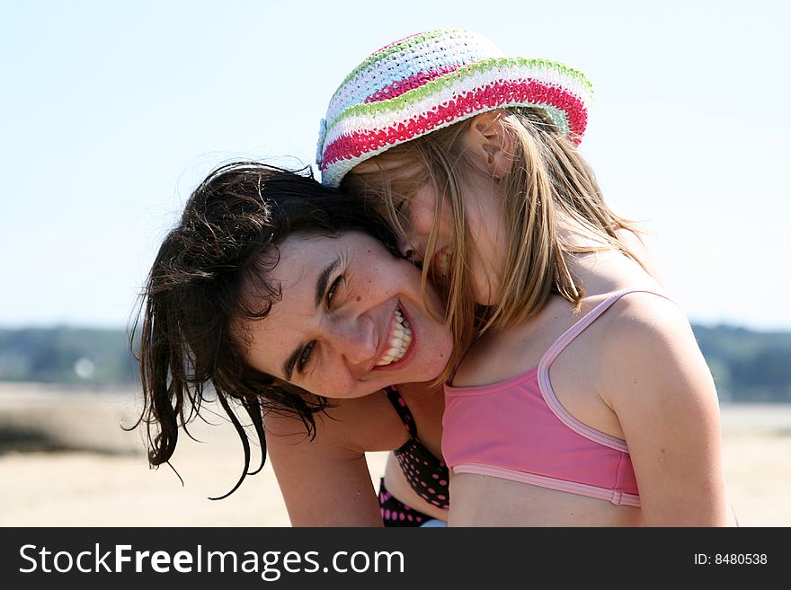 Mother and girl hugging at the beach