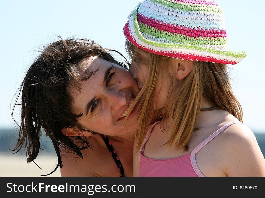 Woman and girl at the beach kissing