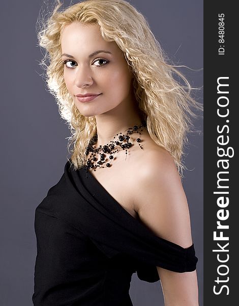 Beautiful curly blond girl with black dress and necklace portrait. Beautiful curly blond girl with black dress and necklace portrait