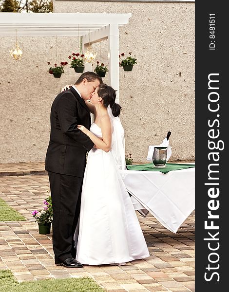 Newlyweds kissing on stone path in garden. Newlyweds kissing on stone path in garden
