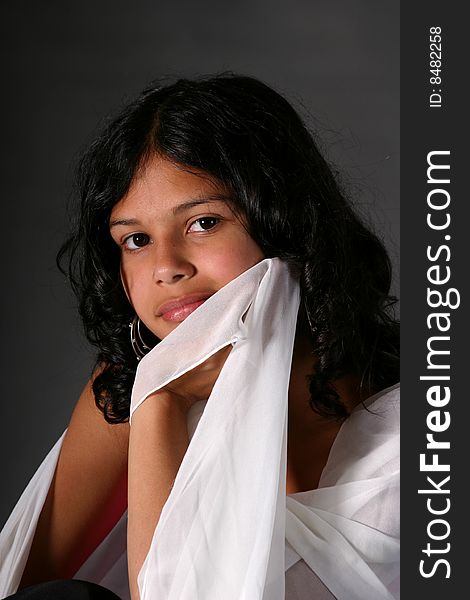 Attractive young Hispanic woman draped in a white scarf. Attractive young Hispanic woman draped in a white scarf