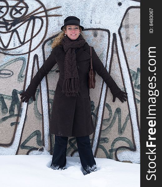 Girl with brown hat standing by concrete wall with graffiti