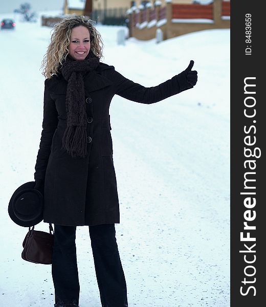 Curly girl hitchhiking in winter time