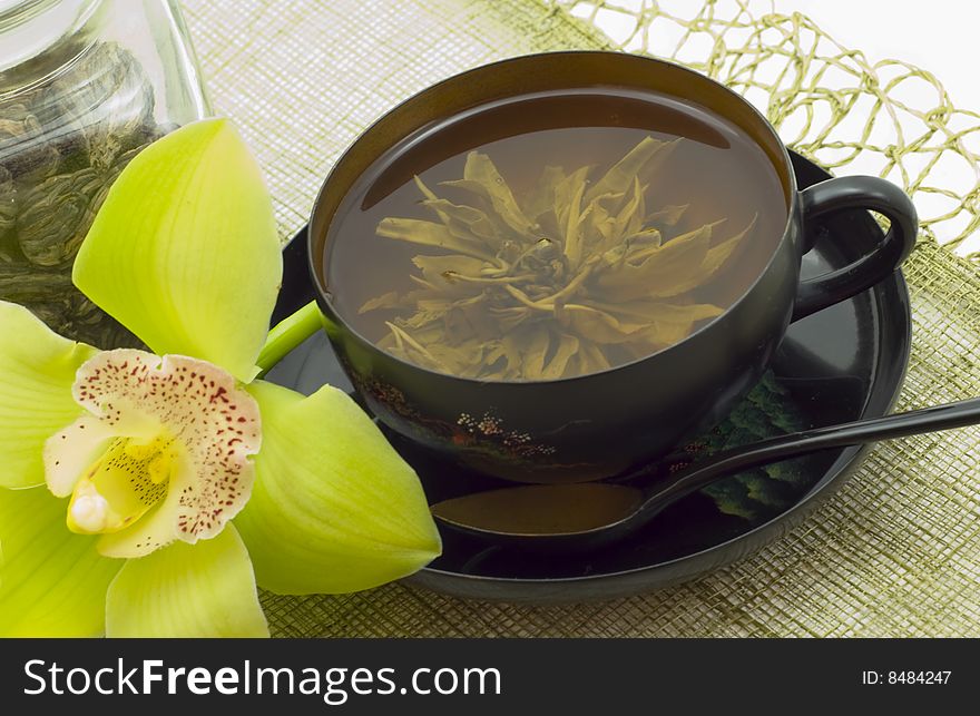 Green tea in beautiful black cup, devices and flower