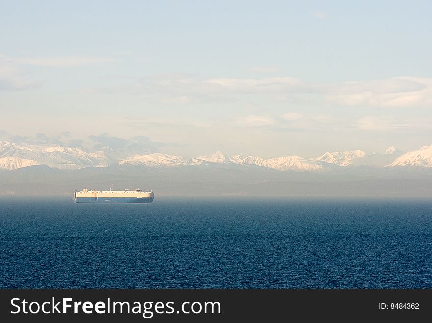 A car carrier in the gulf of Trieste (gulf of Koper) with italian and slovenian Alps in the background.