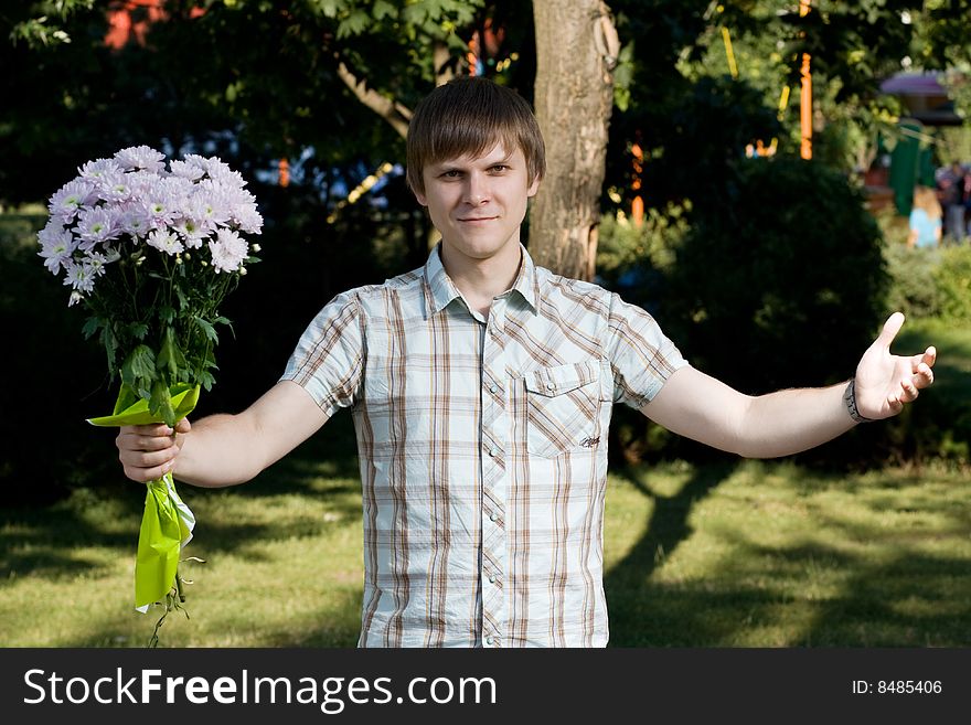 A boy is on a date in a park. He is holding a bouquet of flowers in his hand. A boy is on a date in a park. He is holding a bouquet of flowers in his hand.