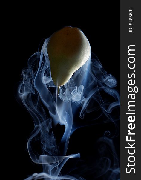 Green pear enveloped by smoke on a black background. Green pear enveloped by smoke on a black background