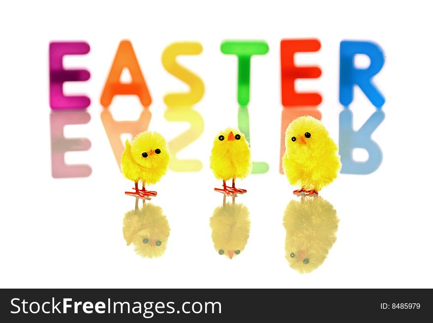 Baby chicks reflected in white with colorful easter word in background