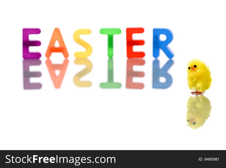 Baby chick reflected in white with colorful easter word in background