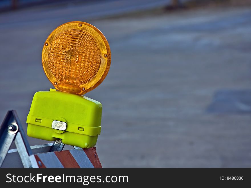 A orange and yellow construction light mounted on a barricade. A orange and yellow construction light mounted on a barricade