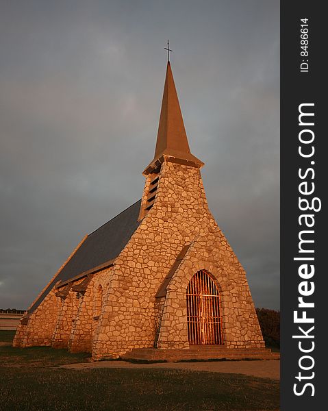 An old stone church at sunset, located on top of a cliff at Etretat, France. An old stone church at sunset, located on top of a cliff at Etretat, France.