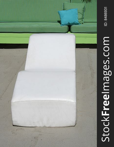 White longe chair with green couch in the background. White longe chair with green couch in the background.