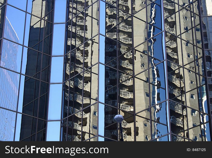 Glass building downtown with multiple structures reflected. Glass building downtown with multiple structures reflected.