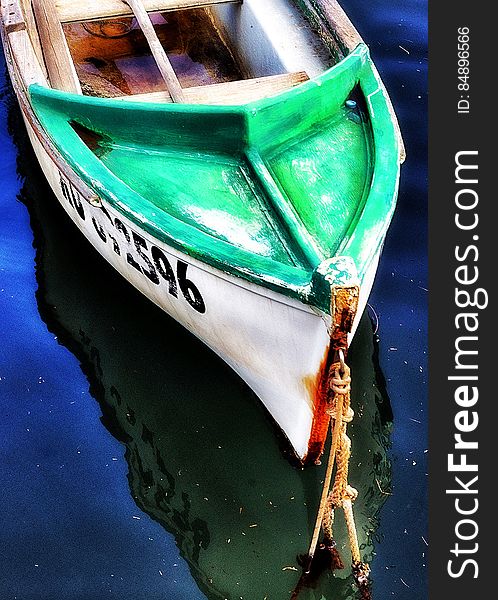 Close up of the bow of a wooden boat painted green and white moored in water. Close up of the bow of a wooden boat painted green and white moored in water.