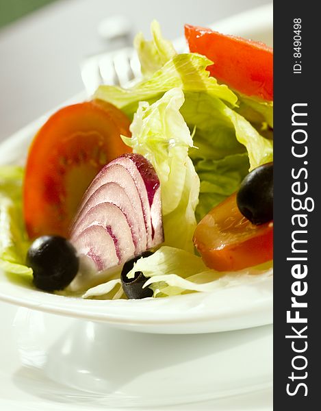 Fresh salad with onion tomato and olives in a white plate
