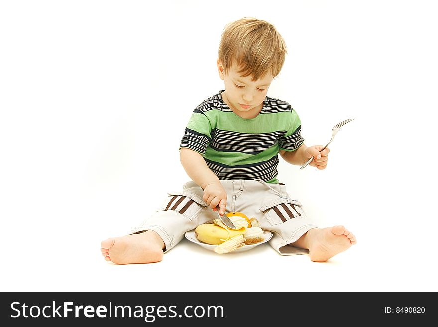 Young boy eating fruits with fork and knife over white