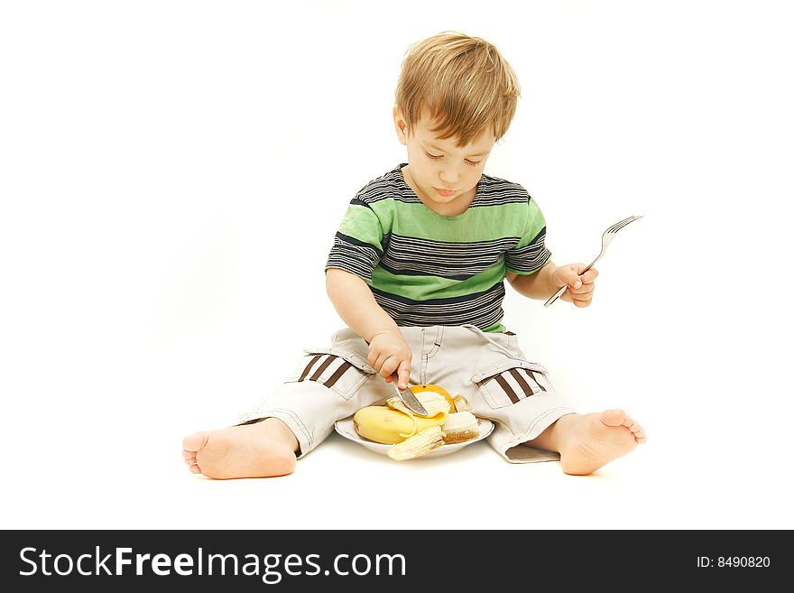 Young boy eating fruits with fork and knife