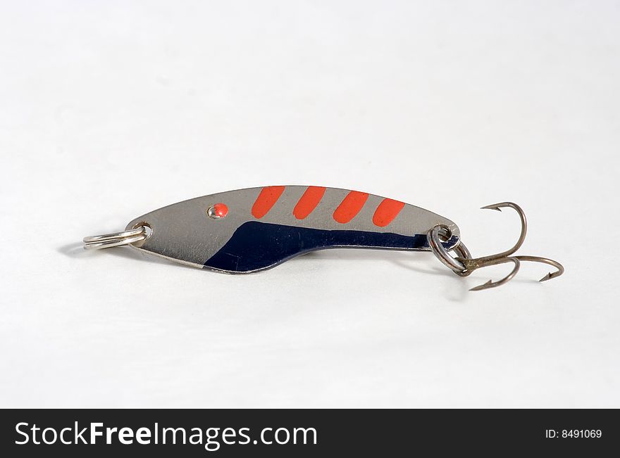 Spoon bait of the blue red colour from metal with hook on white background