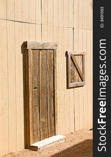 An unpainted wooden barn door and window