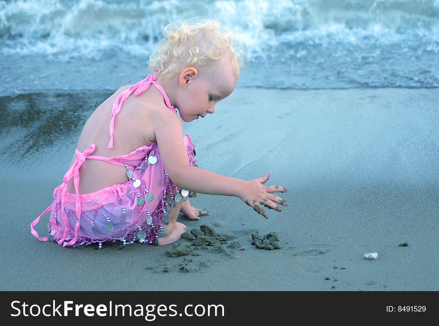 The little girl played on the beach sand. The little girl played on the beach sand
