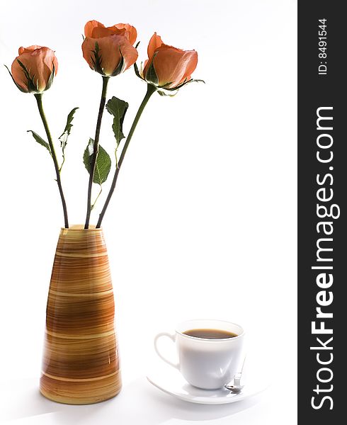 Roses in a base, and a cup of coffee. Roses in a base, and a cup of coffee