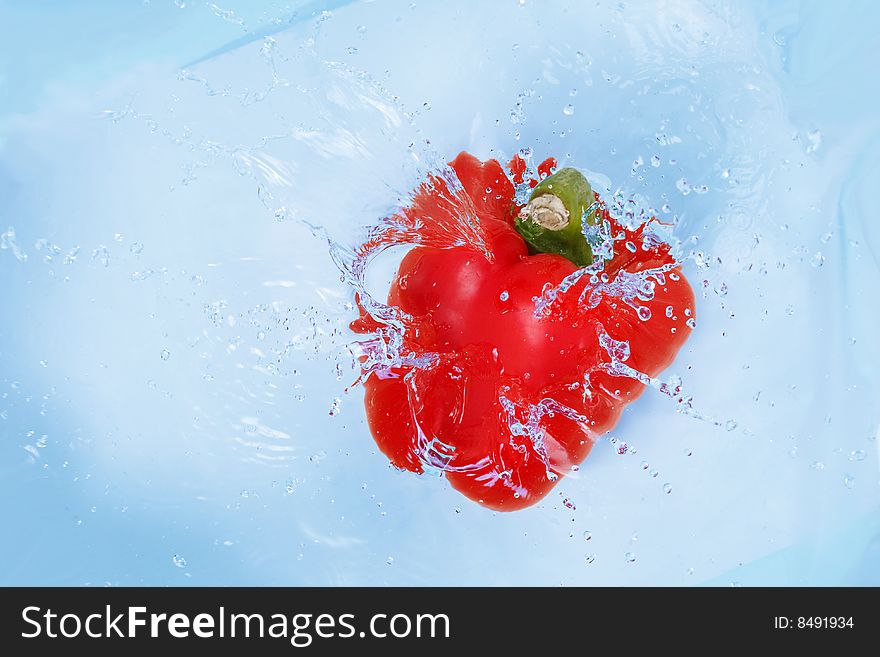 Red pepper falling into blue water