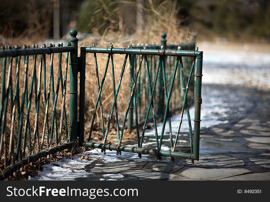 A green fencing in Tsinghua University after snow.The snow is  on the flagging.