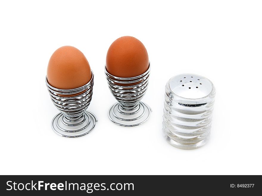 Two eggcups with eggs next to a salt can