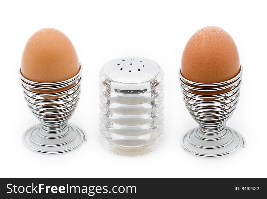 Two eggcups with a salt can in the middle, isolated on white