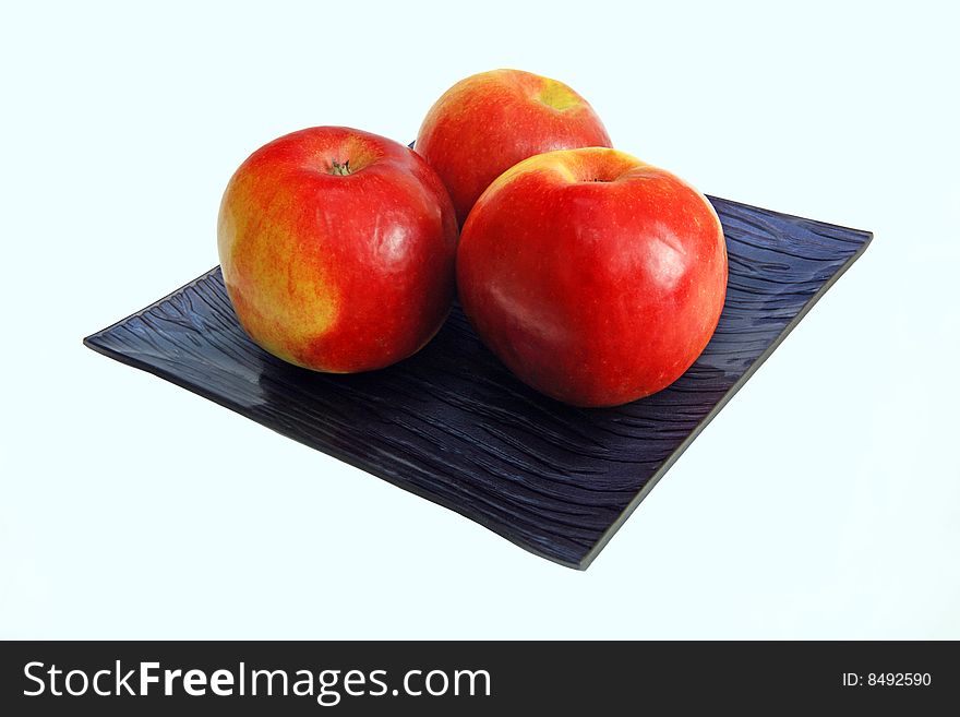 Three red apples on a glass dish